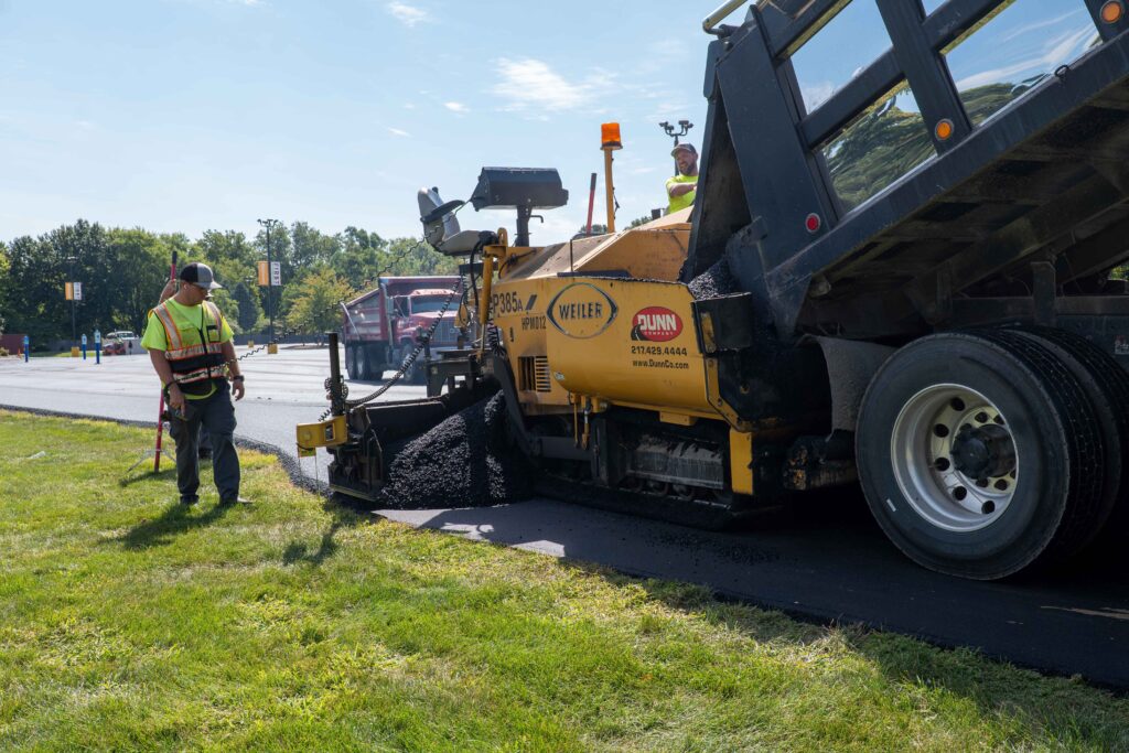 Asphalt paving machine laying hot mix asphalt on commercial parking lot