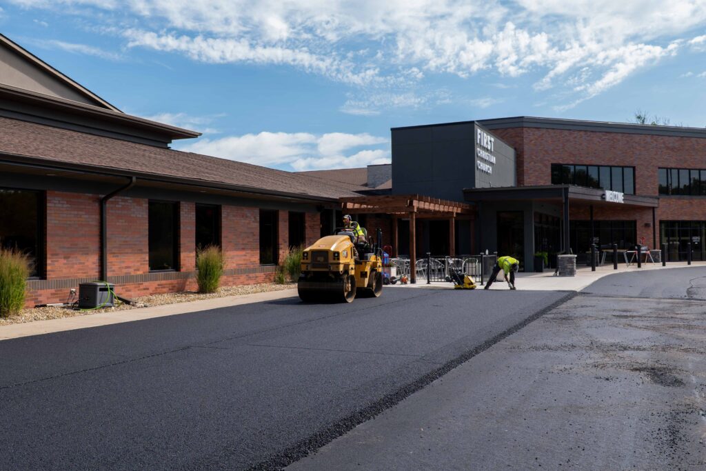 Roller compacting new asphalt at church entrance driveway