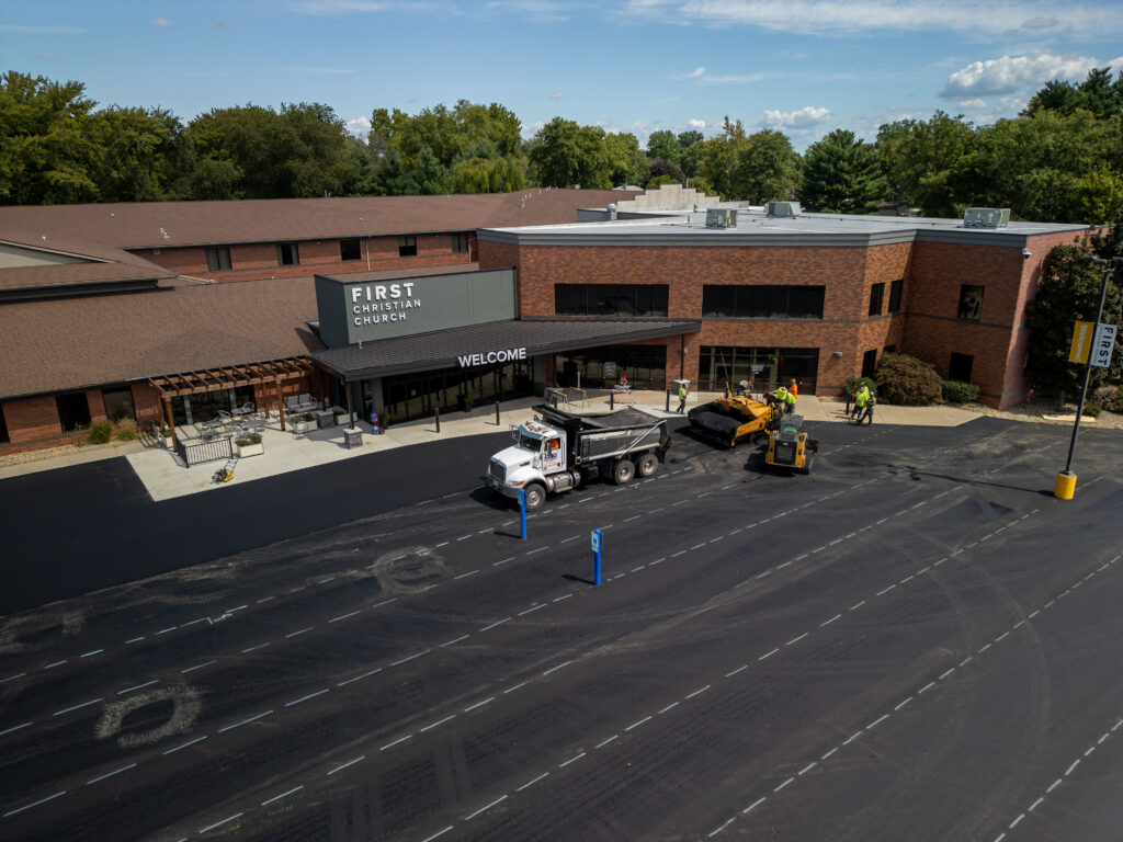 Asphalt paving work at church front entrance parking lot with paving equipment and crew