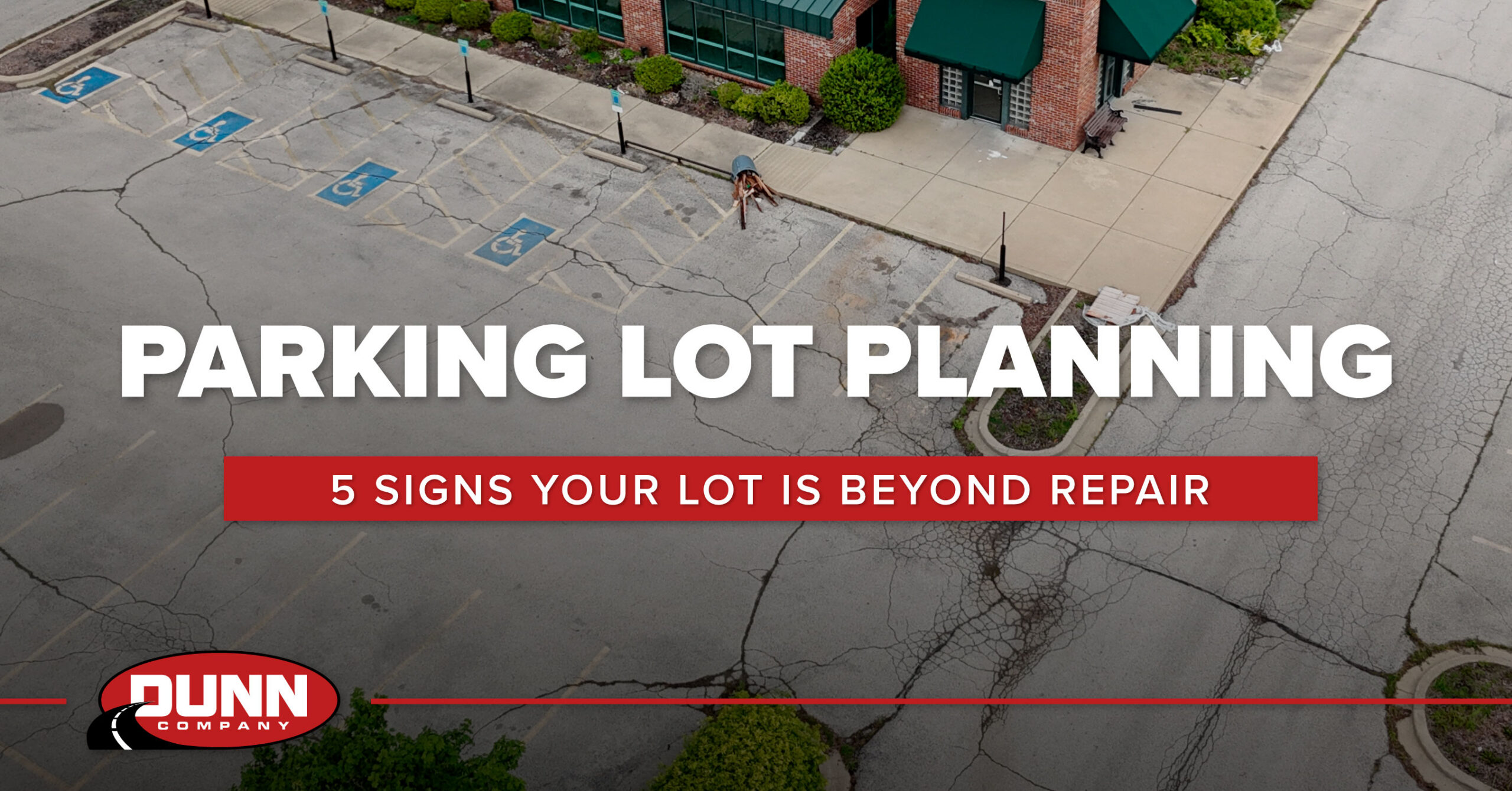 Aerial view of a cracked commercial parking lot showing widespread pavement deterioration that requires more than routine maintenance.